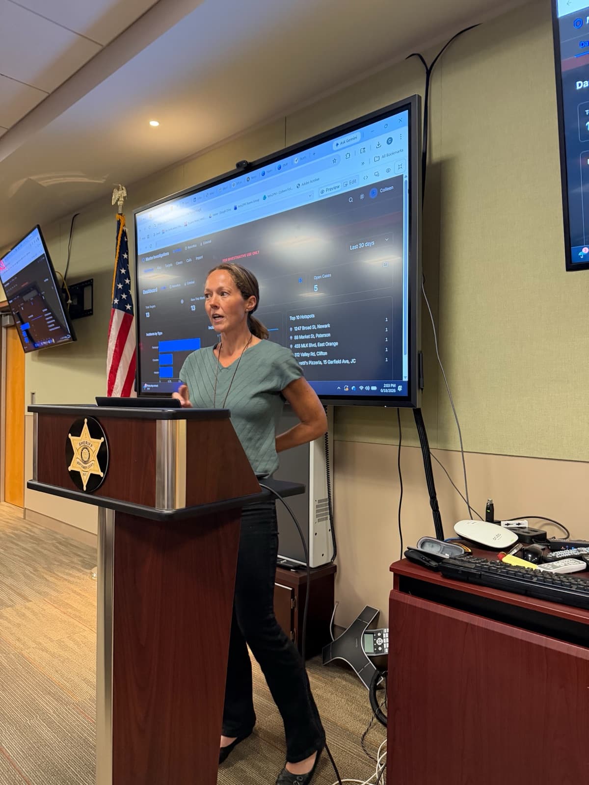A summit attendee presenting the app she built, with a live dashboard on the screen behind her